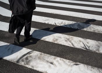 Uma senhora com um vaso atravessa a rua